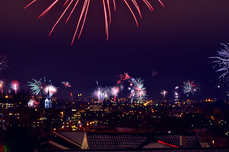 Vibrant fireworks light up the night sky over a city. Perfect for celebrations or festive events.