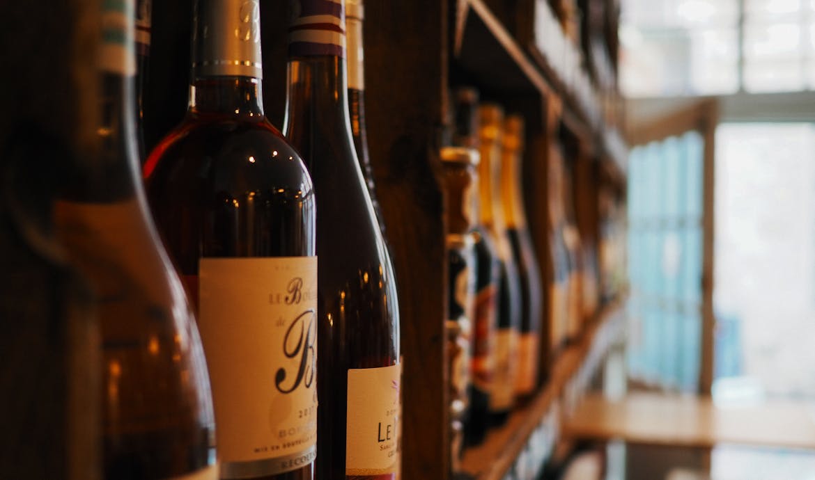 Close-up of wine bottles on shelves in a cozy bar setting in Lille, France.