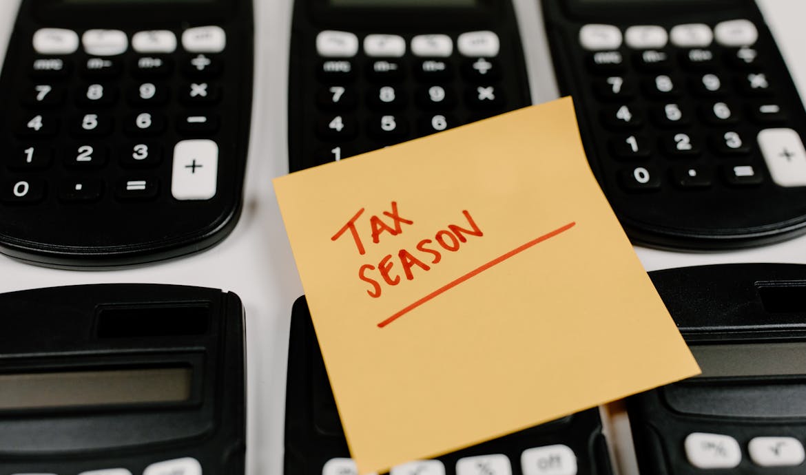 Close-up of calculators and a sticky note labeled 'Tax Season', symbolizing tax preparation.
